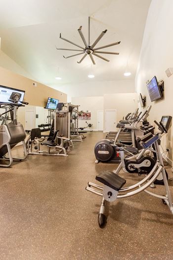 a gym with various exercise machines and televisions